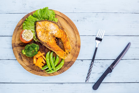 Salmon steak with vegetable on wooden plateの写真素材