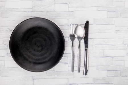 Empty black plate and kitchenware on wooden table backgroundの写真素材