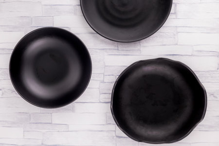 Empty black plate and kitchenware on wooden backgroundの写真素材