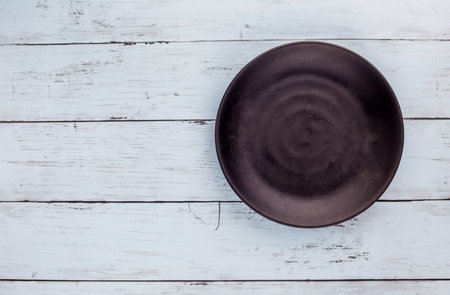 Empty black plate and kitchenware on blue wooden backgroundの写真素材