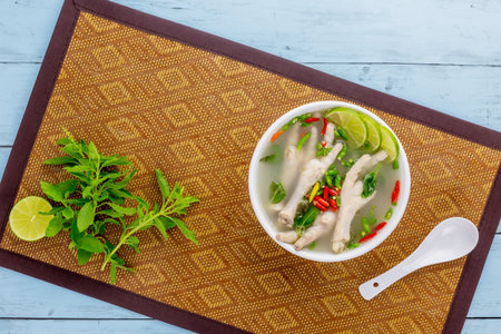 Chicken feet spicy soup tasty Thai food on blue wooden tableの写真素材