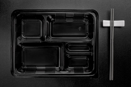 Empty black plastic food container on black tableの写真素材