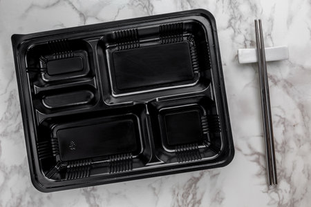 Empty black plastic food container on marble backgroundの写真素材