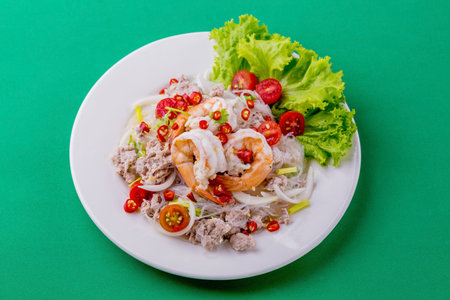 Spicy glass noodles with minced pork and shrimp on green backgroundの写真素材