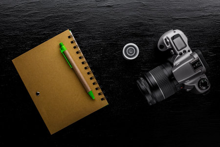 Recycle notebook and old camera on black tableの写真素材