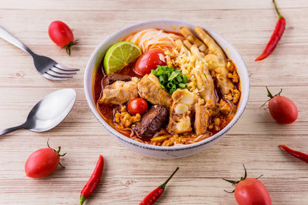 Rice vermicelli wiith northern Thai pork and feet chicken curry on wooden background