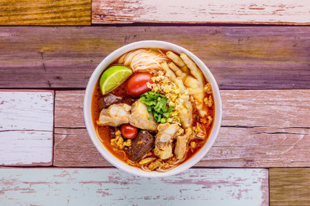 Rice vermicelli with northern Thai pork and feet chicken curry on wooden backgroundの写真素材
