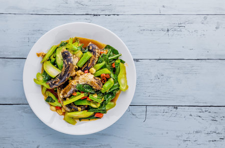 Stir fried kale with canned fish, Thai food on blue wooden backgroundの写真素材