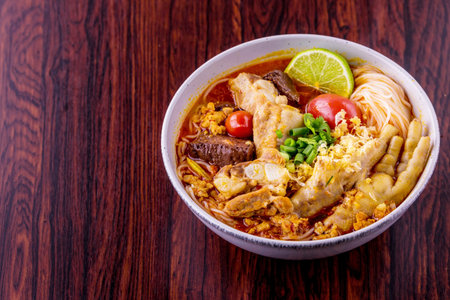 Rice vermicelli wiith northern Thai pork and feet chicken curry on wooden backgroundの写真素材