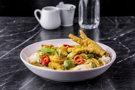 Rice noodles with chicken green curry Thai cuisine on dark marble backgroundの写真素材