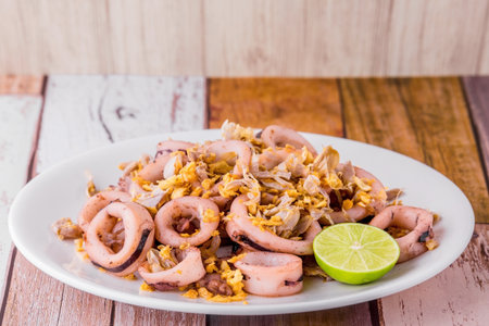 Fried squid with garlic on dark wooden background