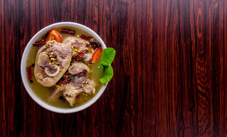 Spicy soup with pork leg on dark wooden background