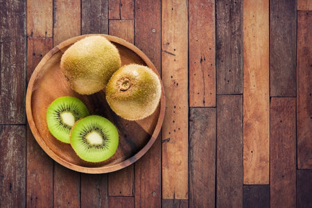 Kiwi fruit on wooden plate dark table backgroundの写真素材