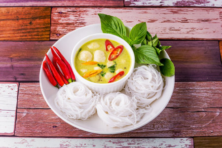 Rice noodles with green curry meatballs on wooden table