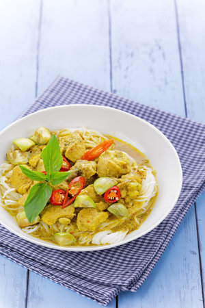 Rice noodles with chicken green curry Thai cuisine on bue wooden backgroundの写真素材