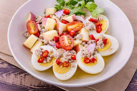 Spicy apple salad with pork and egg on dark wooden backgroundの写真素材