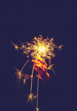 hands holding sparkler on dark background, close upの写真素材