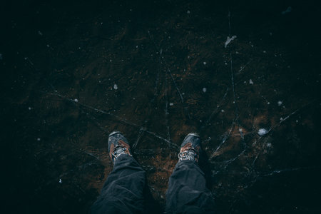 Man standing on the cracked ice and kicking it on the clear lakeの写真素材