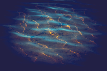 wallpaper of calm water waves on a pond. Golden reflections from the rising sun