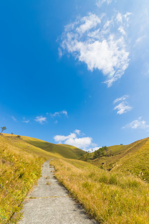 Hiking trail on mountain under blue sky with white cloudsの写真素材