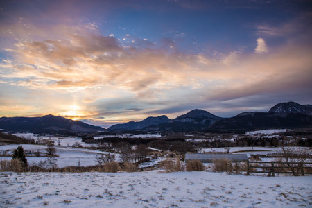 Beautiful winter landscape and dawn with snow-capped mountains in the backgroundの写真素材