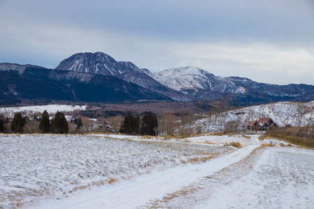 Winter landscape with snow-capped mountains and village in the distanceの写真素材