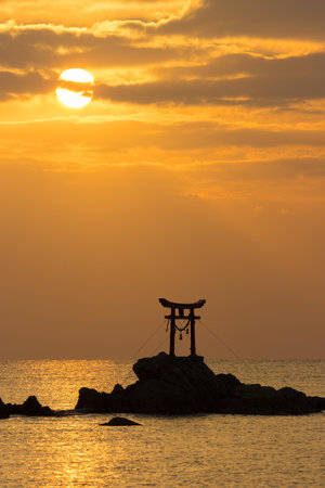 Silhouette of torii gate at sunset in the sea.の写真素材