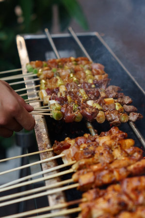 photo of hand holding skewer to be cookedの写真素材