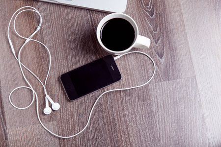 A cup of coffee with smart phone on wood table.の写真素材
