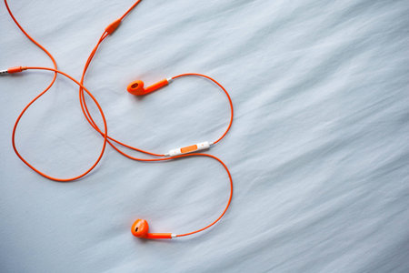 Orange color earphone on fabric background.の写真素材