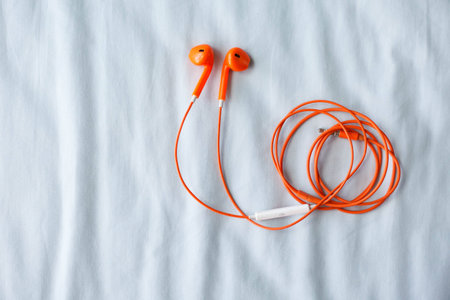 Orange color earphone on fabric background.の写真素材
