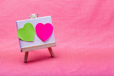 wooden easel with pink and green color heart on canvas background..の写真素材