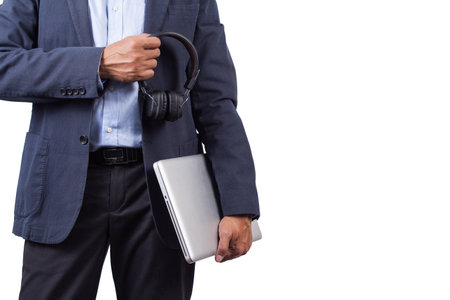 Business man standing holding headphone and laptop in hand.の写真素材