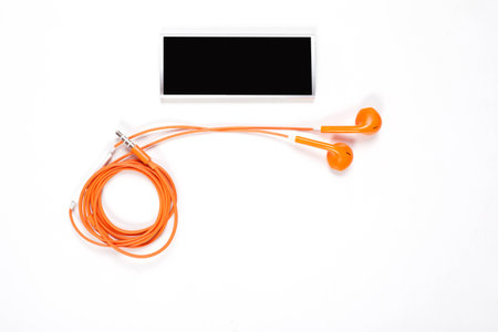 orange color earphone with music player on white background.の写真素材