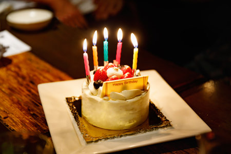 a birthday cake lit by a candleの写真素材