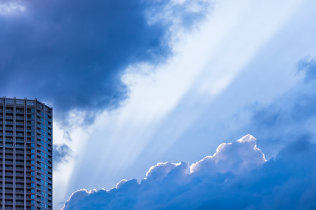 Sunshine and urban buildings visible through the gaps in the cloudsの写真素材