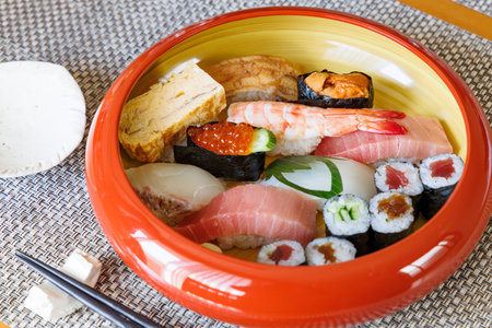 Sushi set in a bowl with chopsticks on the table.の写真素材