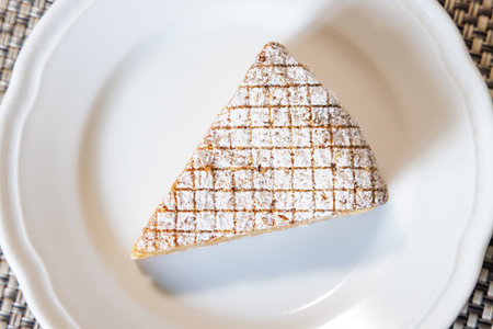 A piece of cake on a white plate on a wicker backgroundの写真素材