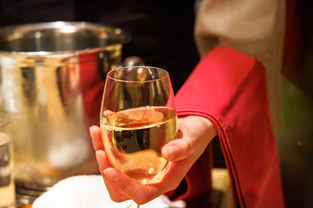 Glass of white wine in the hands of a girl in a restaurantの写真素材