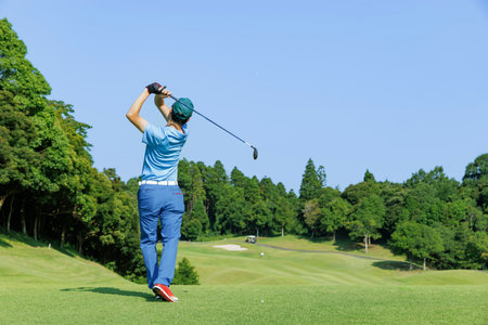 A person taking a shot on a tee ground surrounded by beautiful fresh greeneryの写真素材
