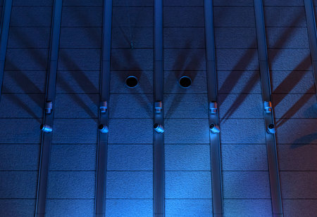 Background image of a textured wall of made concrete, lightly lit by a blue spotlightの写真素材
