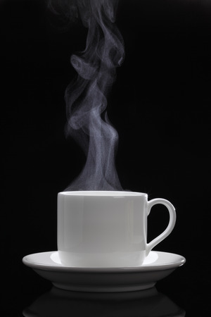 Cup of black coffee with steam on the black backgroundの写真素材