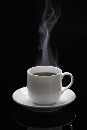 Cup of black coffee with steam on the black backgroundの写真素材