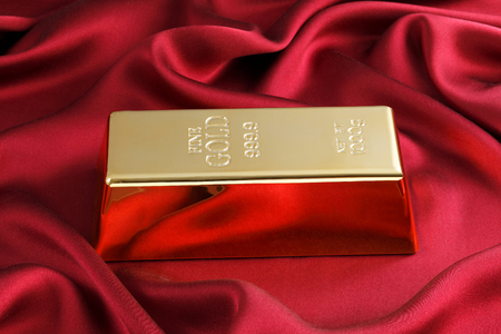 Photo of a 1kg gold bar on red satinの写真素材