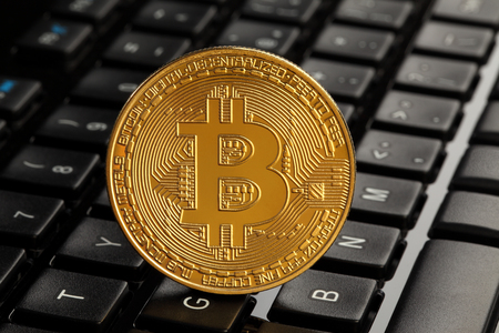 Golden bitcoin (virtual coins) on a top of a keyboardの写真素材