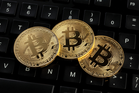 Golden bitcoin (virtual coins) on a top of a keyboardの写真素材