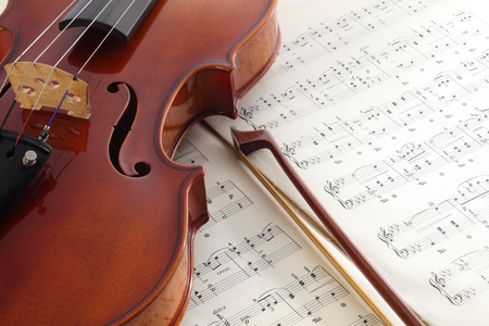 Close-up photo of vintage violin with bow and musical notes.の写真素材