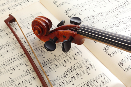 Close-up photo of vintage violin with bow and musical notes.の写真素材