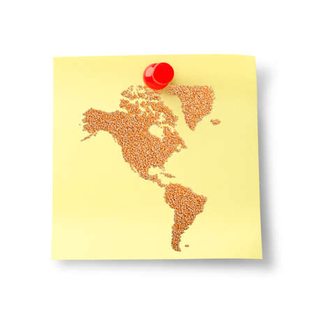 World map made of corn on Yellow sheet of note paper with red push pinの写真素材