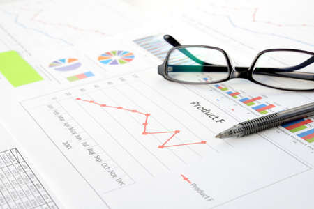 Business charts, ballpoint pens and glasses